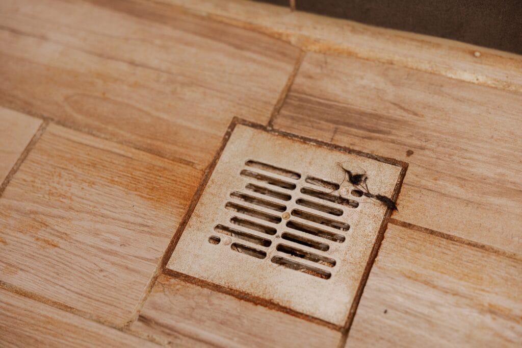 How to Prevent Drain Clogs: Dirty and disgusting shower drain, close up view. Clogged drain with rust stain, hair.