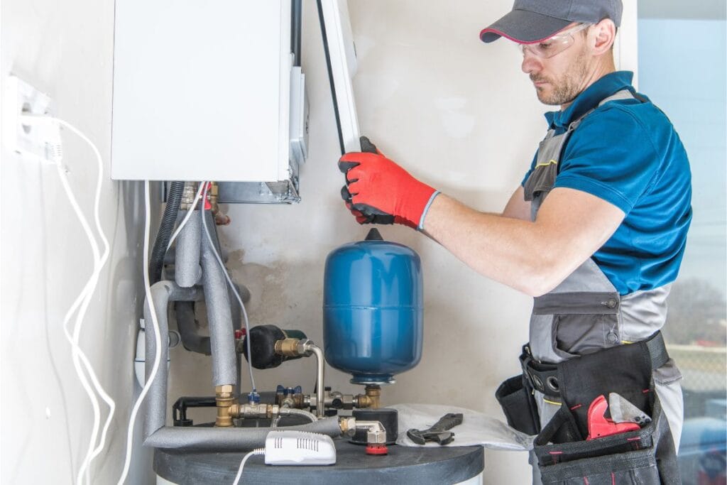 Plumber installing a blue tank in a water heater system, emphasizing maintenance and replacement for energy efficiency.