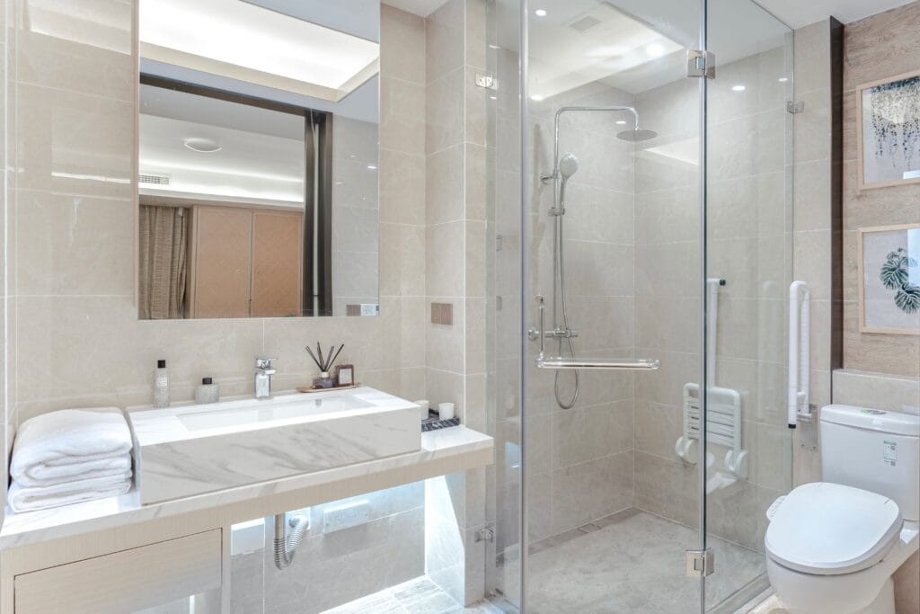 Modern bathroom interior featuring a sleek vanity with a mirror, a shower area with glass doors, and a toilet, emphasizing a clean and functional design for plumbing services.