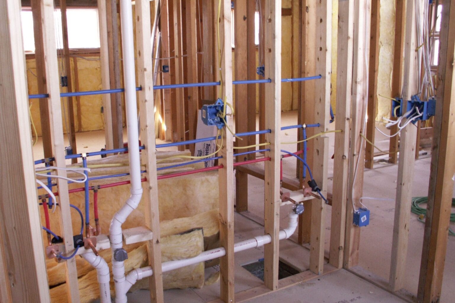 Plumbing installation in a residential setting, featuring pipes, wiring, and framing, relevant to JW Plumbing Pros' services in Northwest Georgia.