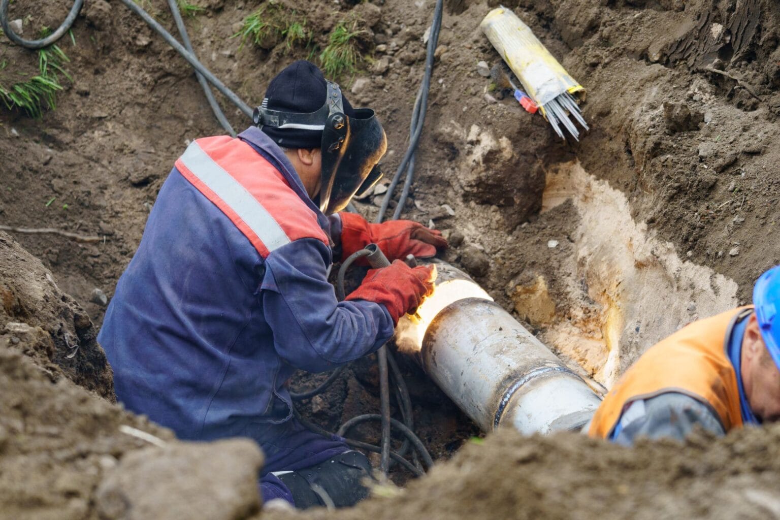 Plumber repairing a pipe in a trench, showcasing expert plumbing services in NorthWest Atlanta.