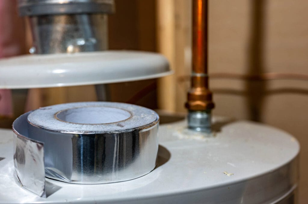 Water heater with copper piping and tape, showcasing plumbing installation details relevant to JW Plumbing Pros' services in water heater maintenance and repairs.