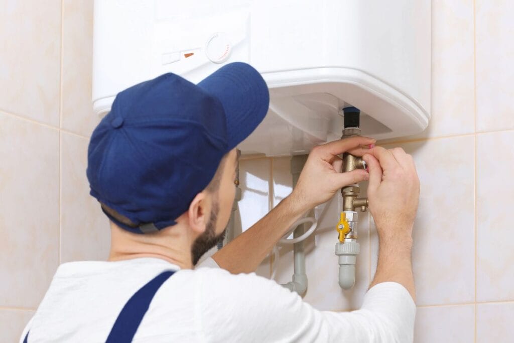 Plumber repairing a water heater, focusing on valves and connections in a residential setting, emphasizing maintenance and replacement for optimal performance.