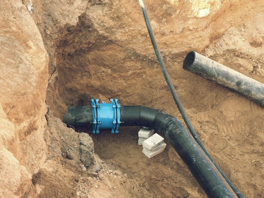 Water line installation with black and blue pipes in a trench, showcasing plumbing repair services relevant to leak detection and water line issues in Atlanta, GA.