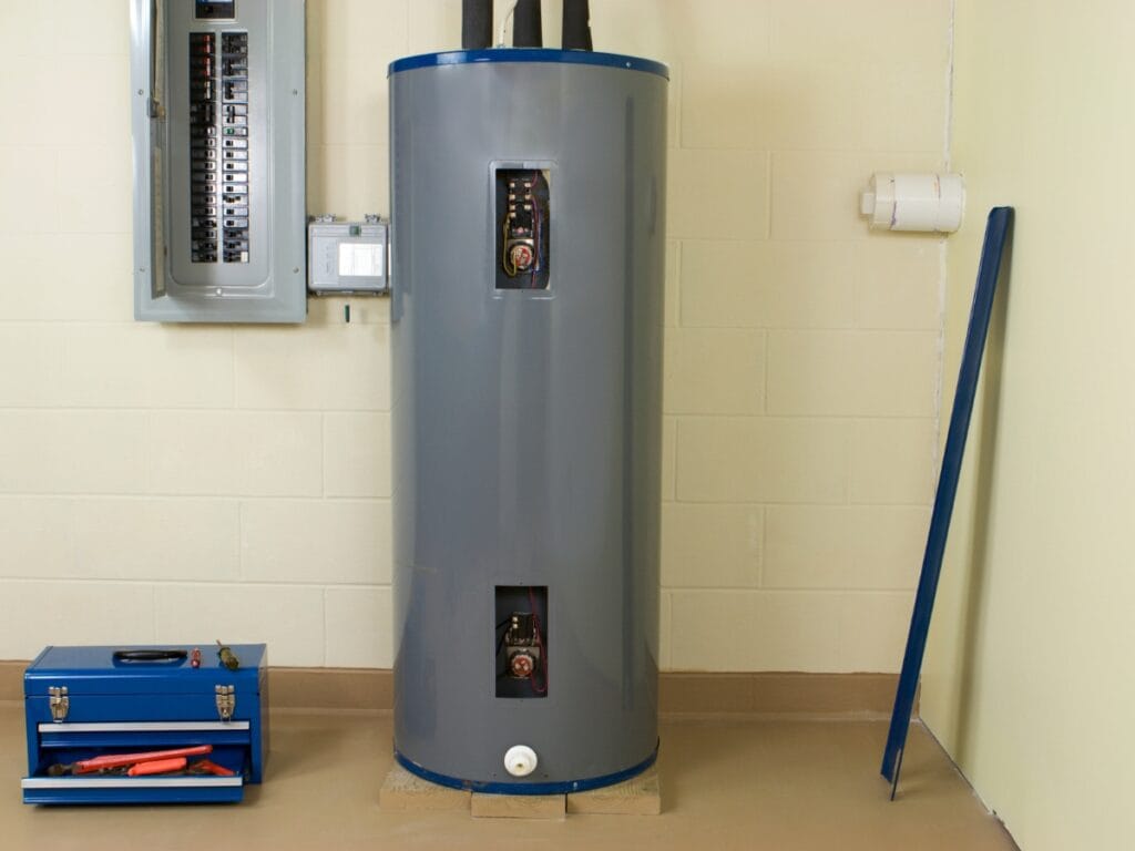 Water heater unit in residential setting, showcasing plumbing connections and tools for maintenance, relevant to water heater repair and replacement considerations.