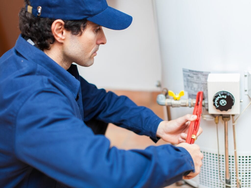 Plumber using a wrench to service a water heater, focusing on maintenance and repair, emphasizing home plumbing solutions.