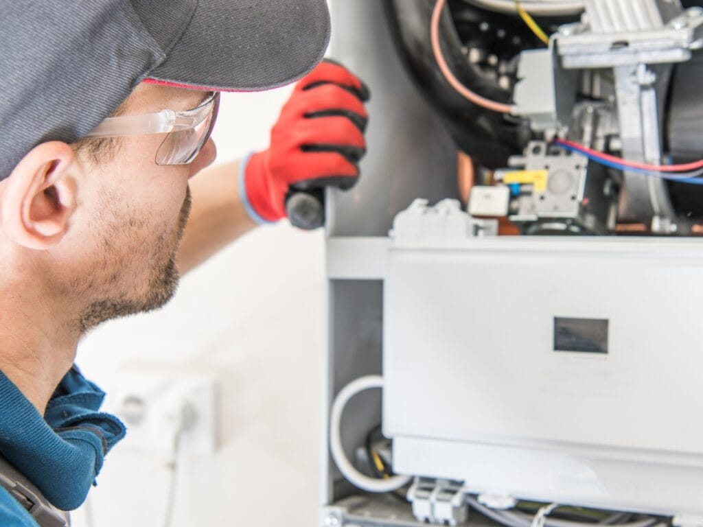 Plumber inspecting a modern water heater unit, highlighting advanced technology and maintenance features for improved energy efficiency and convenience.