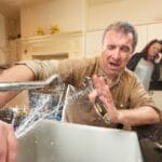 Plumber repairing a sink with water splashing, illustrating common plumbing issues in homes.