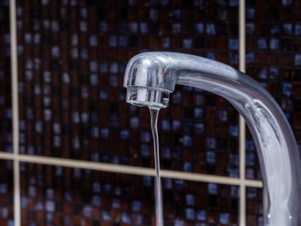 Faucet with water dripping, illustrating low water pressure issues common in older homes.