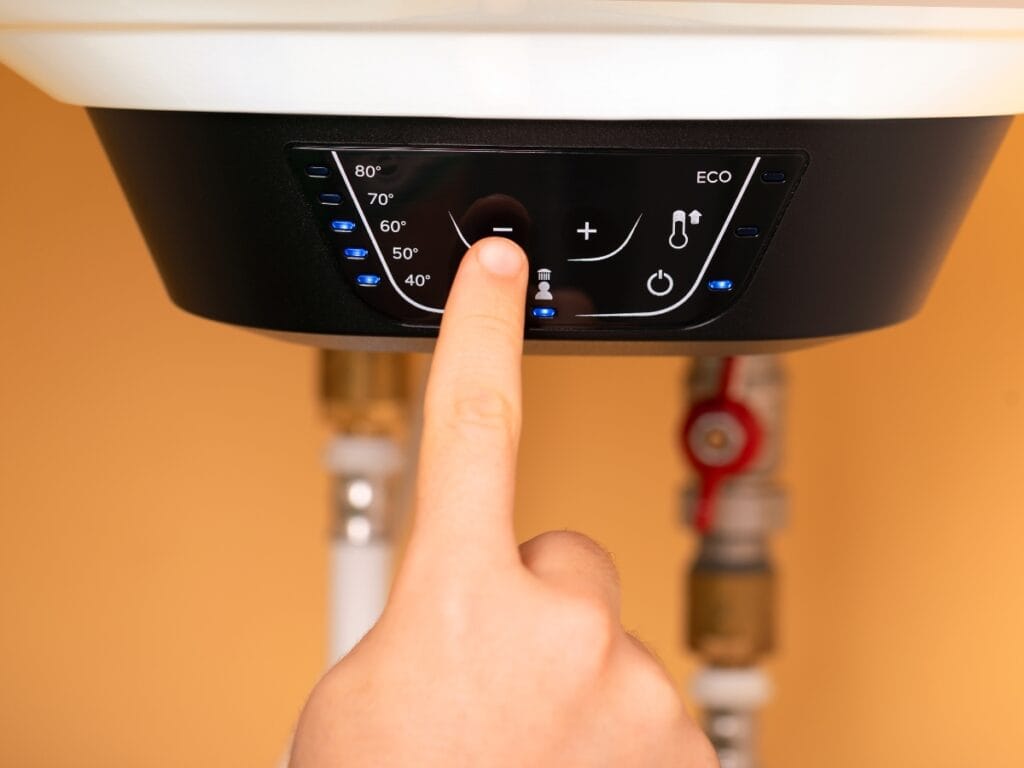 Hand adjusting temperature settings on a tankless water heater control panel, showcasing energy-efficient hot water management.