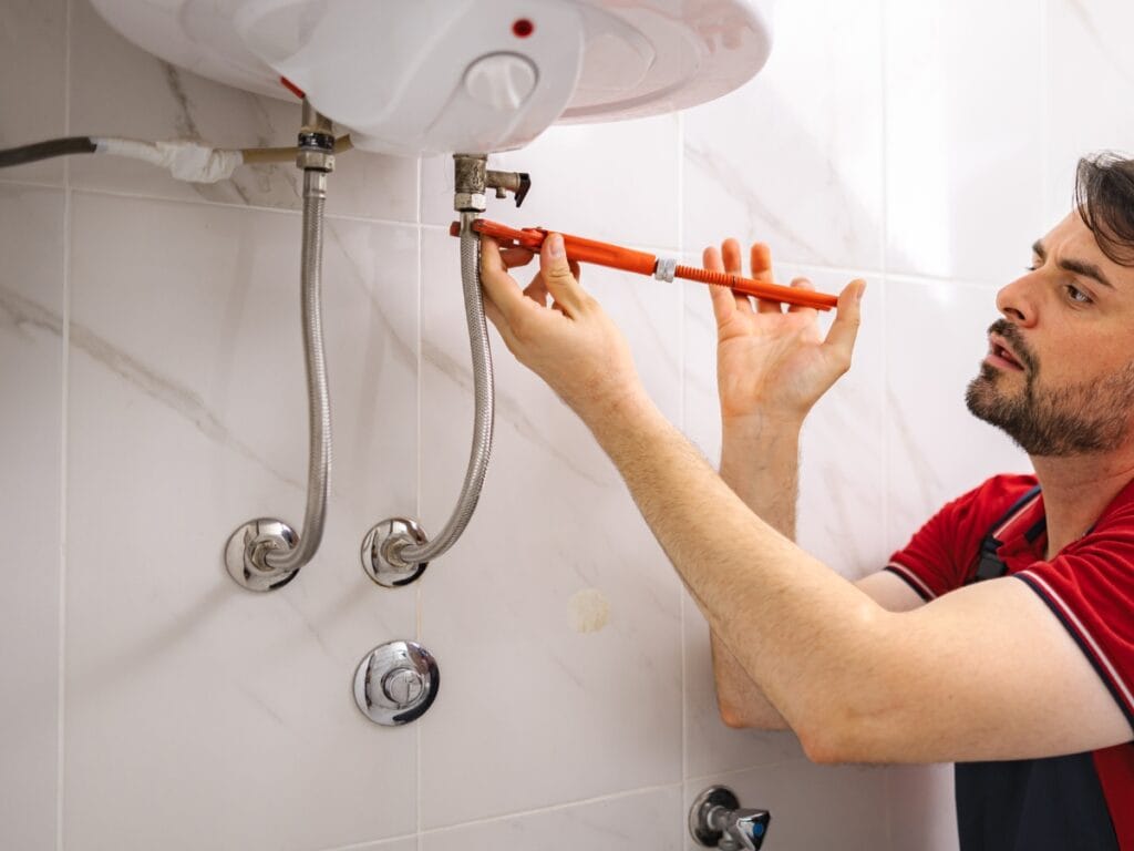 Plumber installing a tankless water heater, demonstrating efficient plumbing practices in a modern bathroom setting.