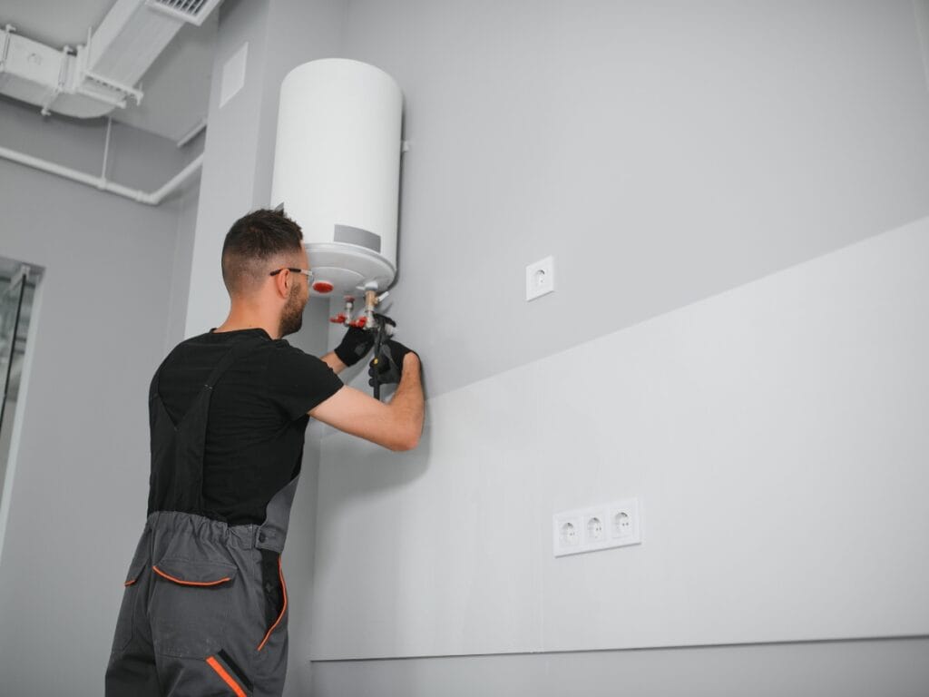 Plumber installing a tankless water heater on a wall in a modern utility space, emphasizing energy-efficient home upgrades.